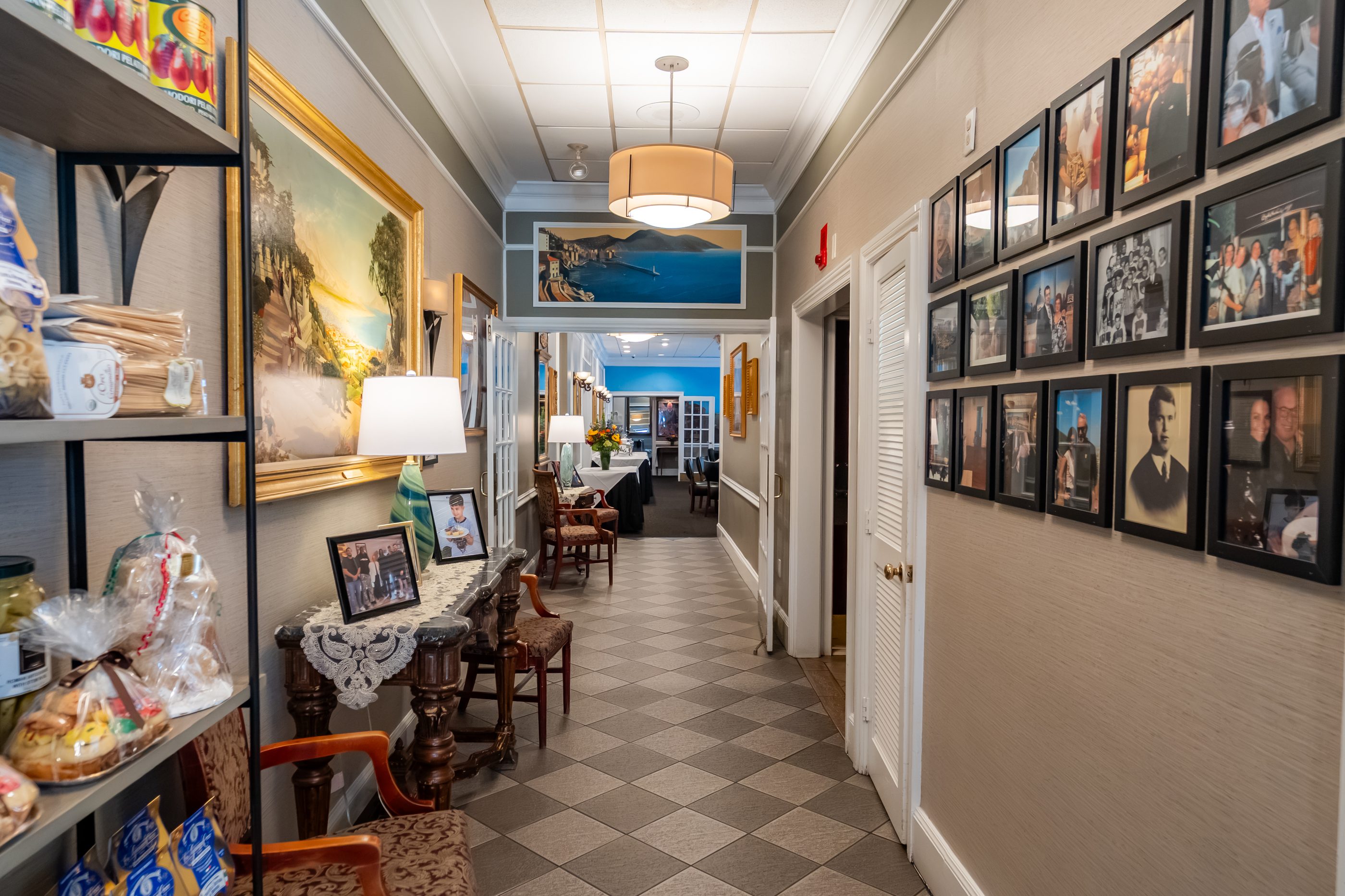 A checkerboard-floor hallway at Luciano’s lined with framed photographs, leading to the Italian market
