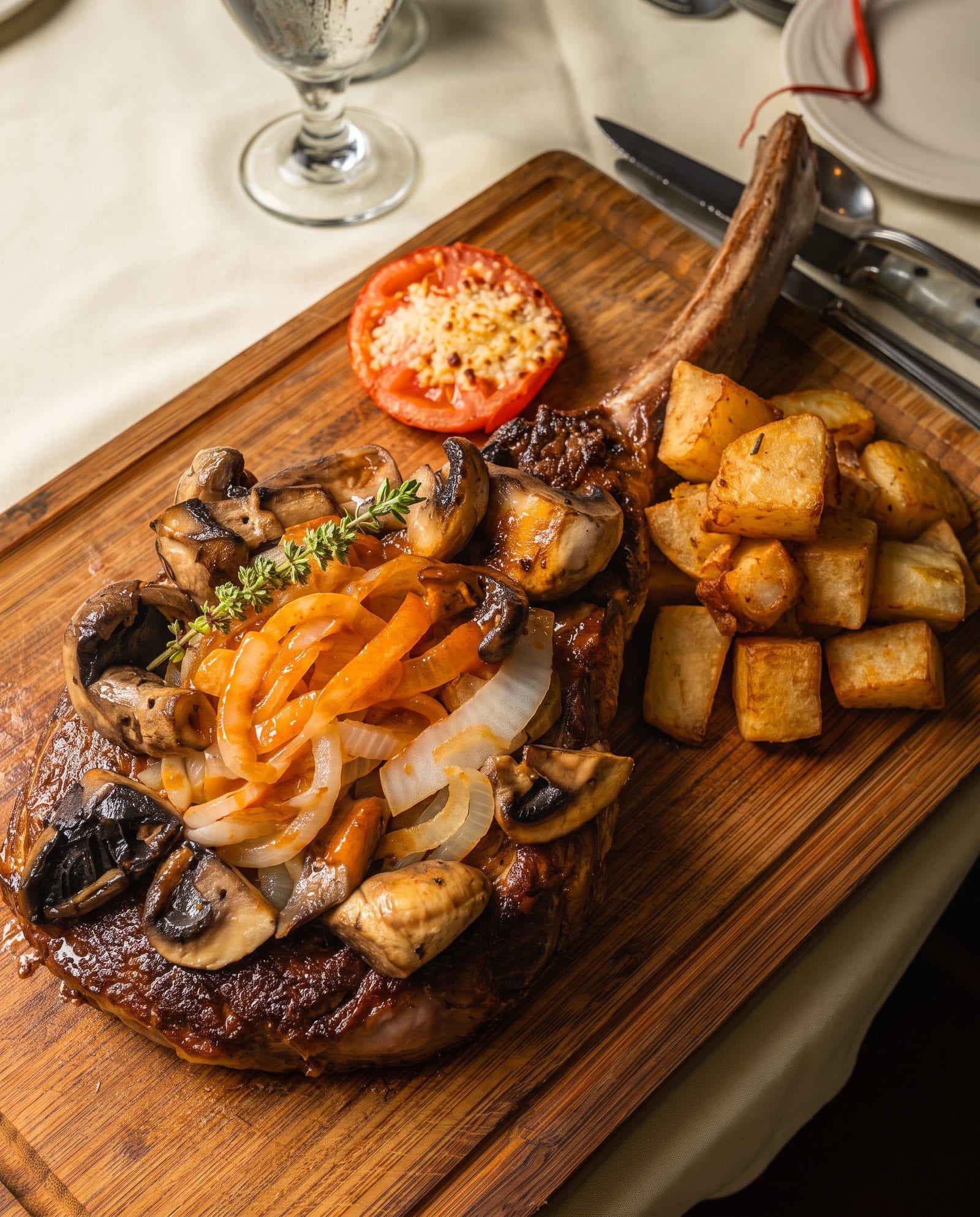 A bone-in chop served on the board with roasted potatoes, mushrooms and onions at Luciano’s