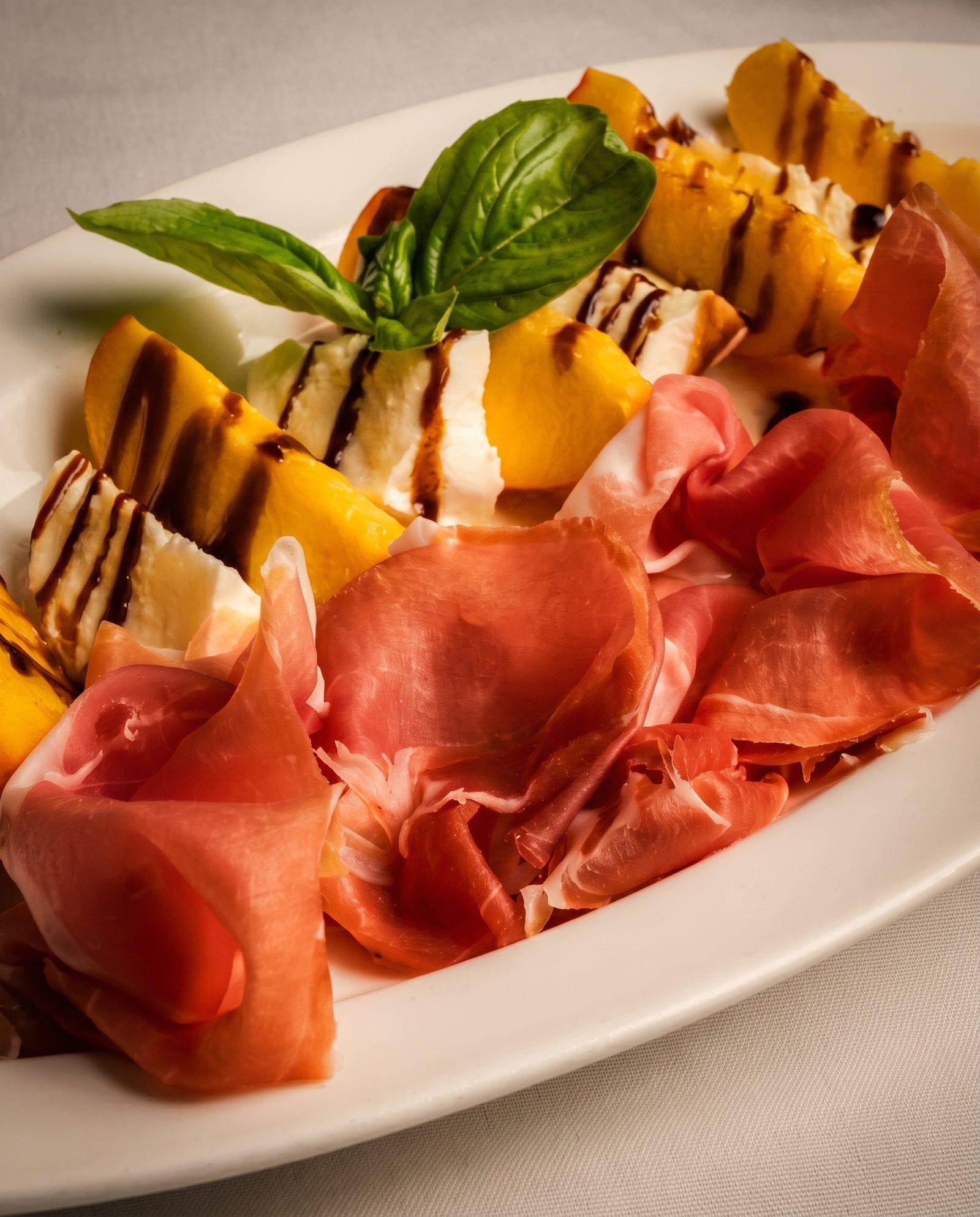 Prosciutto with grilled peach, fresh mozzarella, basil and aged balsamic at Luciano’s