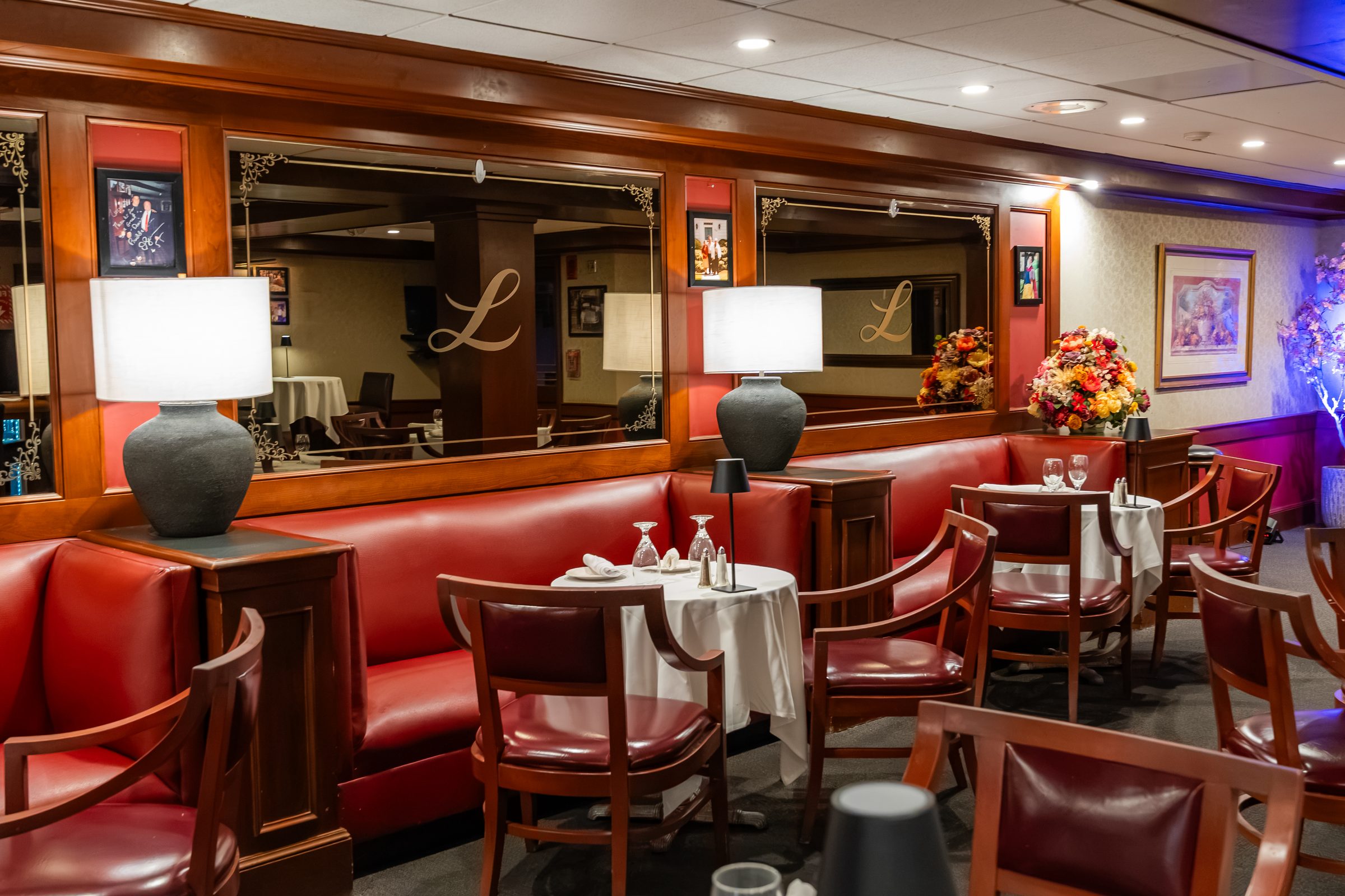 Lamplit banquettes beneath the monogrammed lounge mirrors at Luciano’s