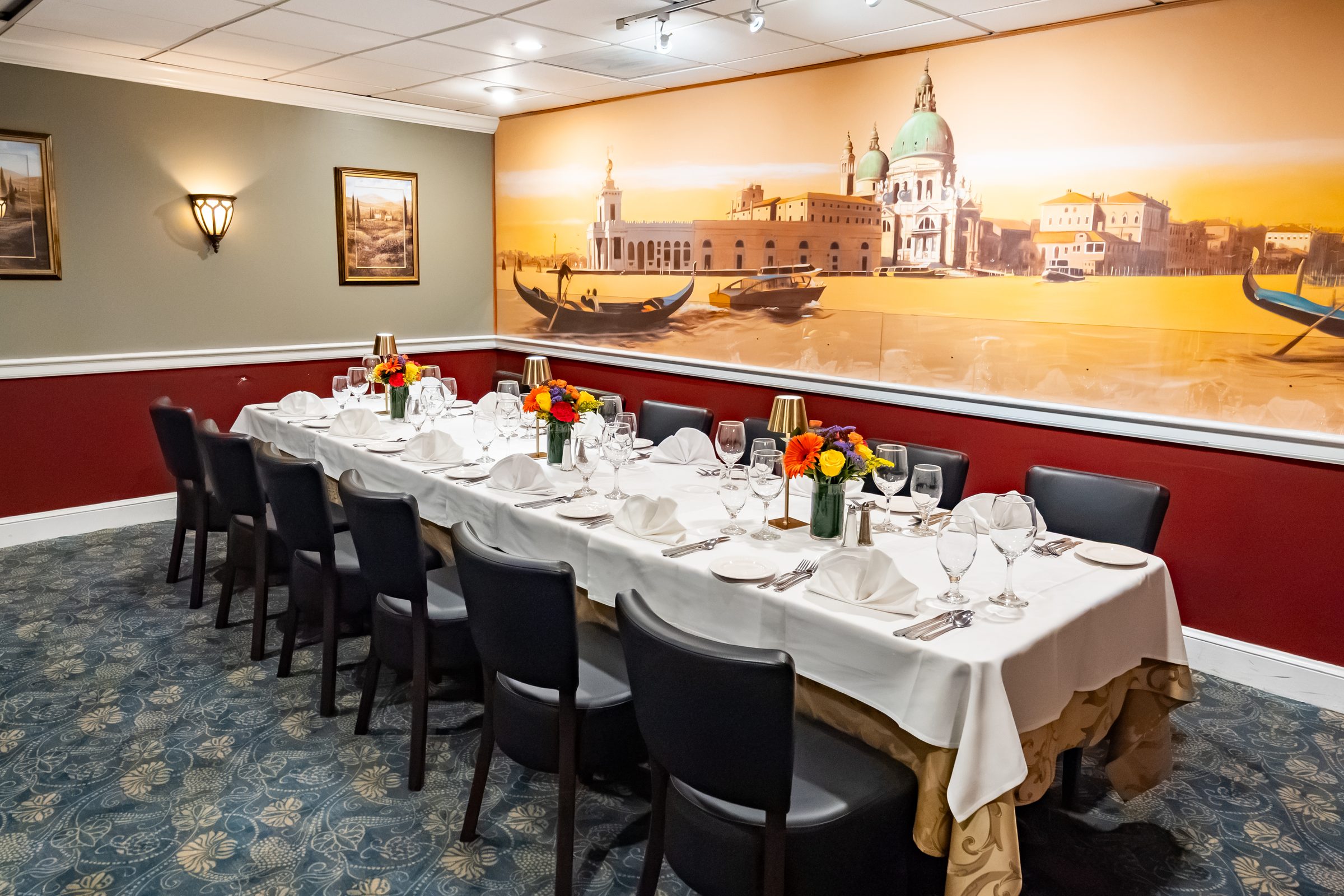 The Charles Room at Luciano’s, one long table set beneath the hand-painted Venetian mural