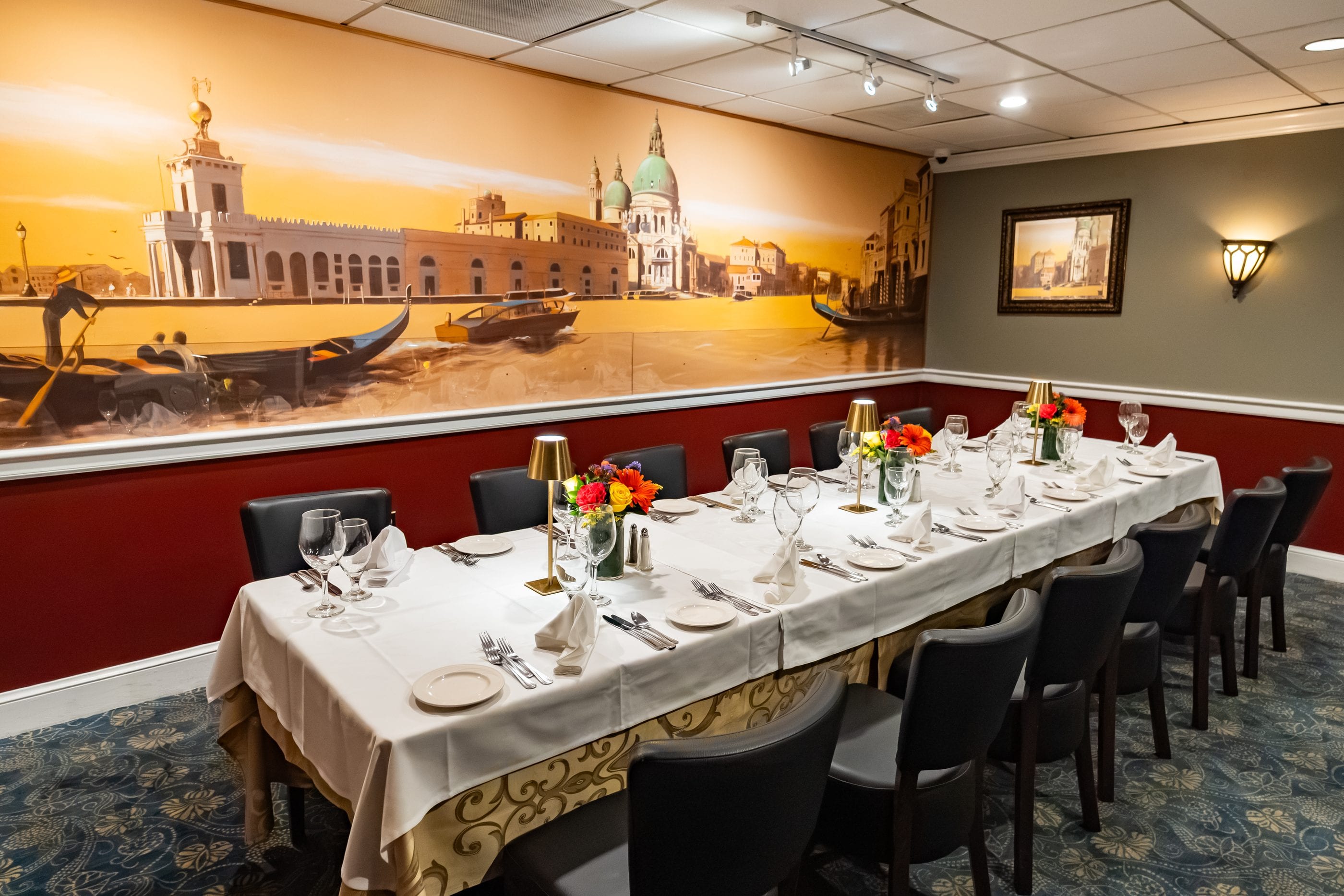 A hand-painted Venetian canal mural above a long table at Luciano’s