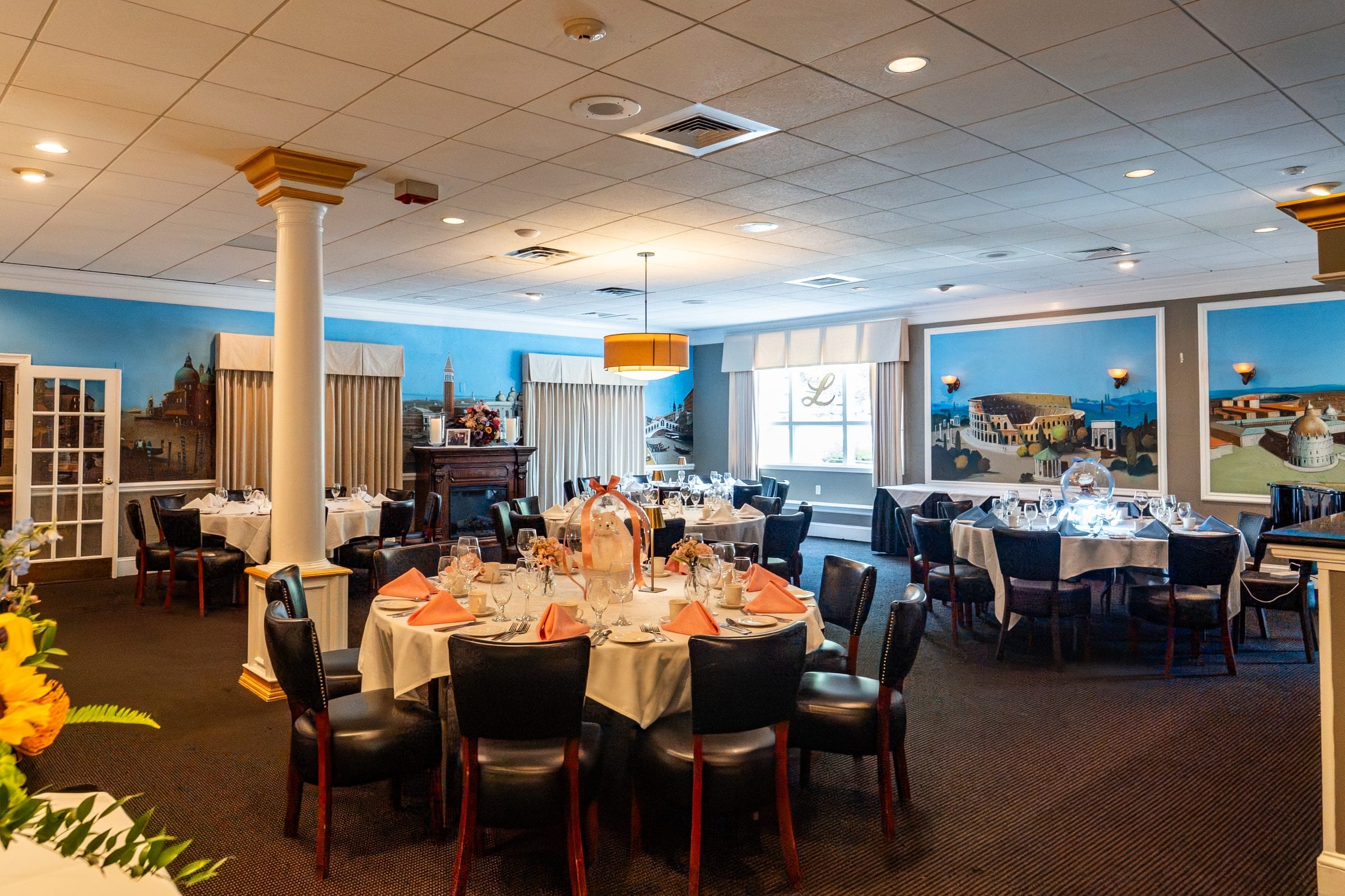A private room with painted Italian landmarks and tables dressed for a party