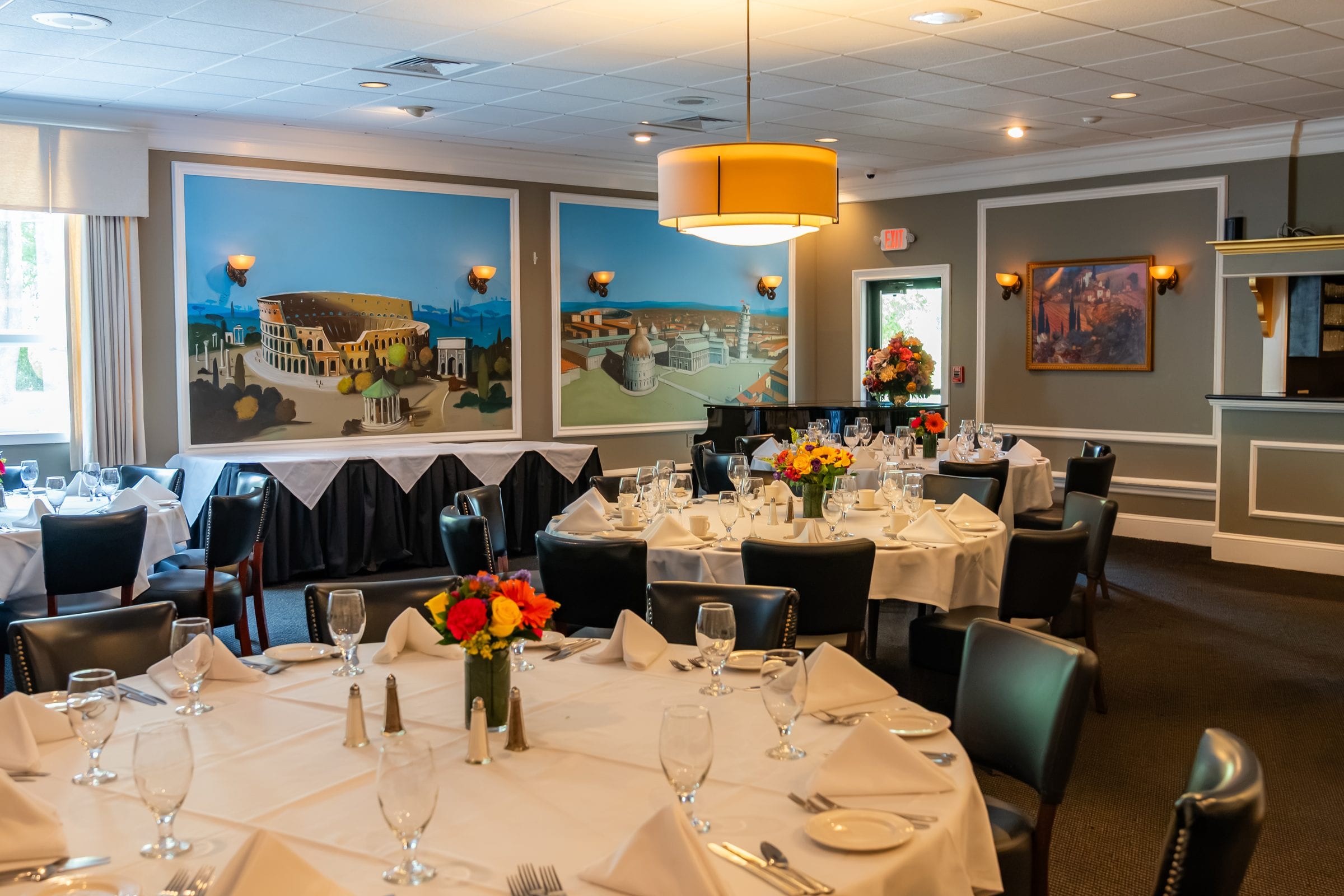 Round tables beneath panoramic painted coastlines in a private room