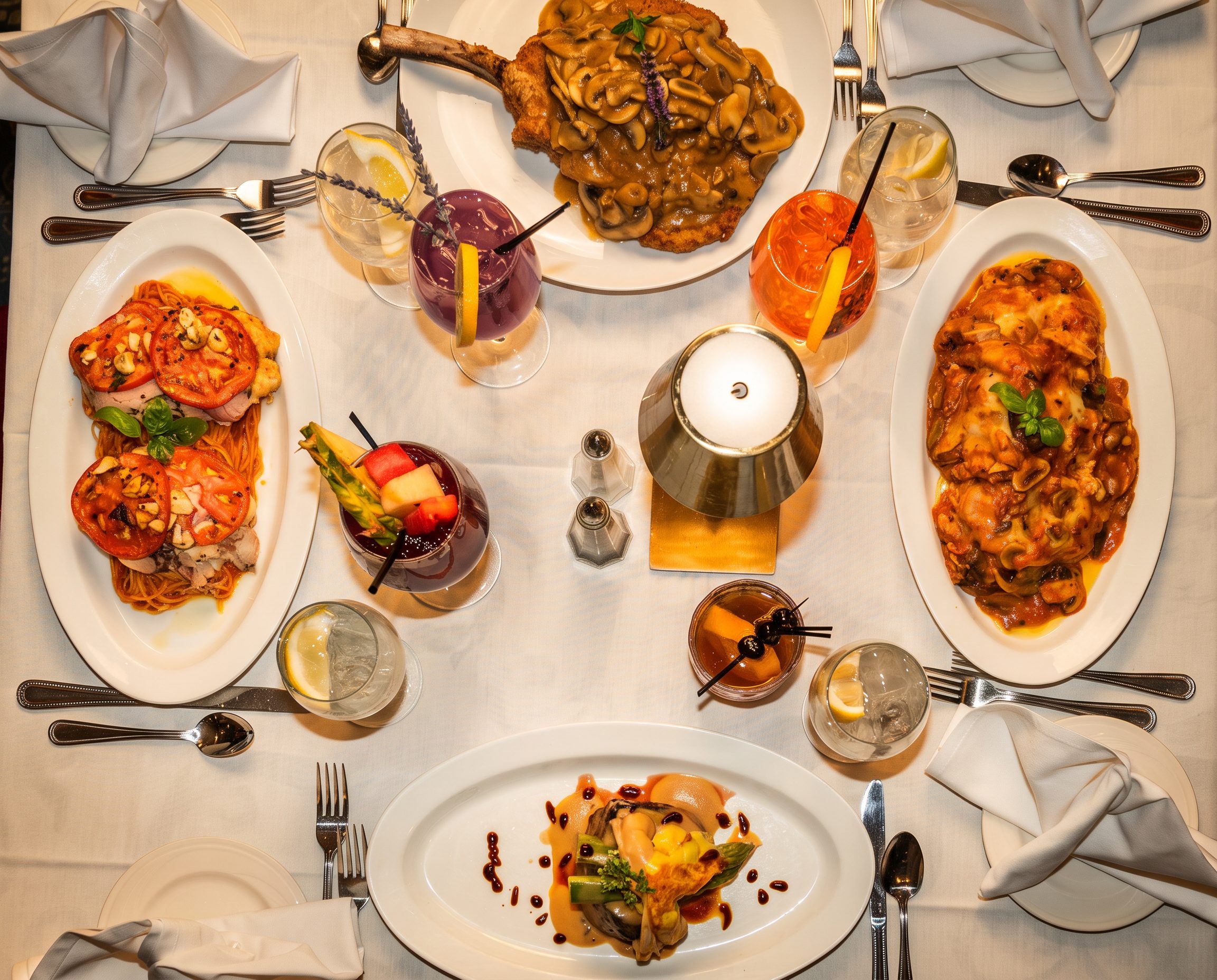 A table at Luciano’s laid with antipasti, pasta, a chop and cocktails, seen from above